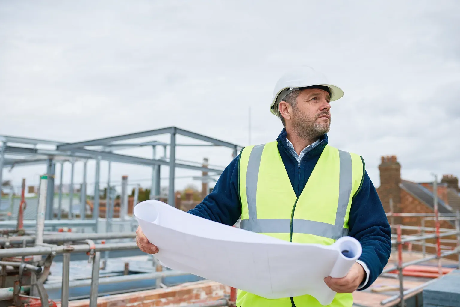 A site manager reviewing drawings on a UK construction site.