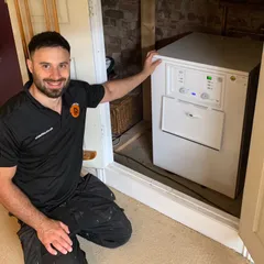 Jordan of Videtta Heating kneeling beside a boiler he has fitted