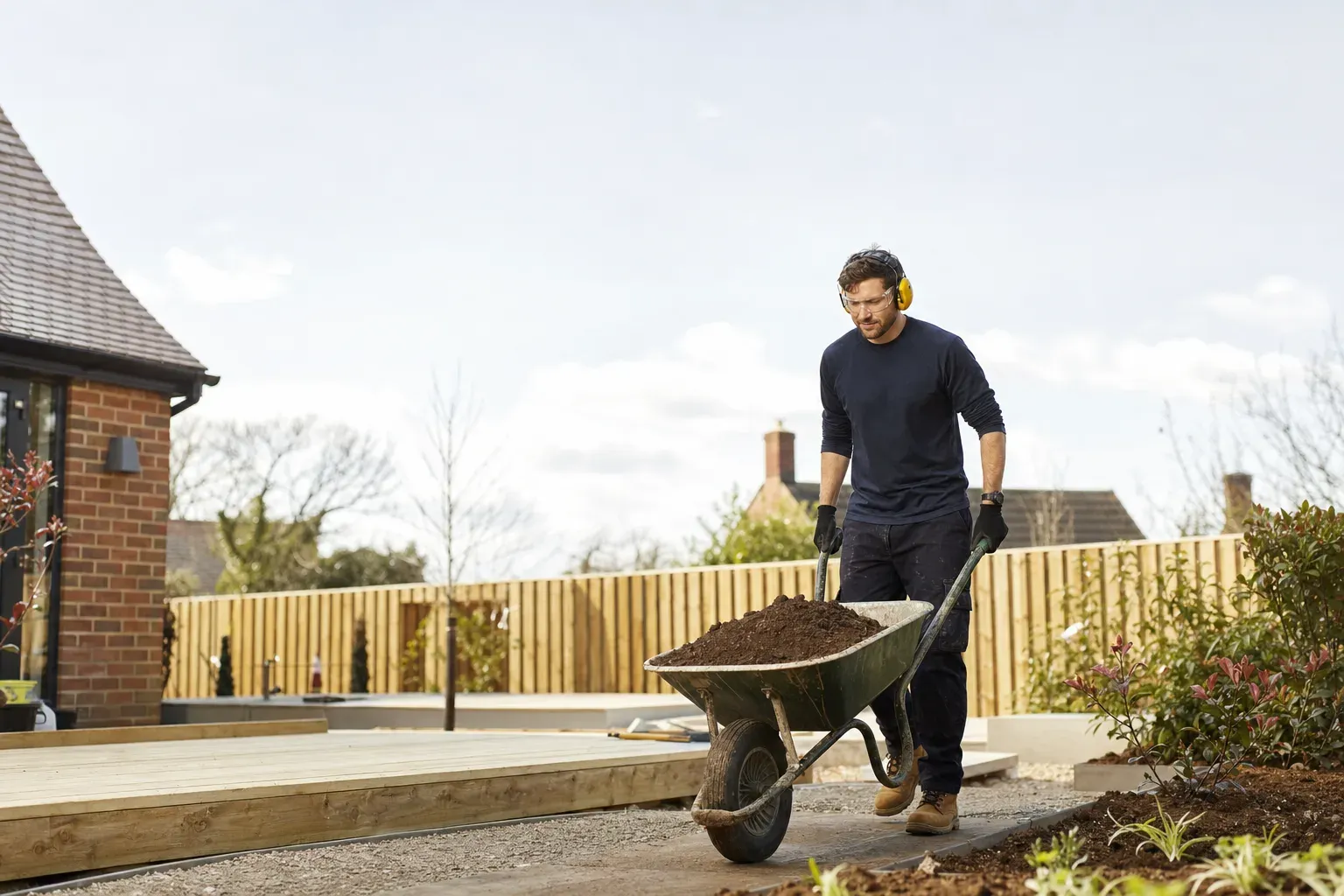 A landscaper building a UK garden with new decking and planting.