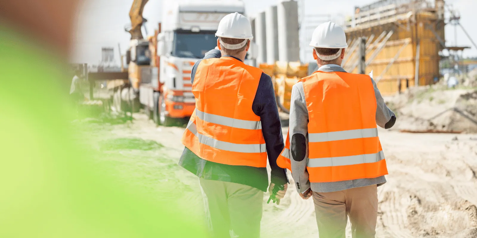 Two site managers in hi-vis walking a construction site together