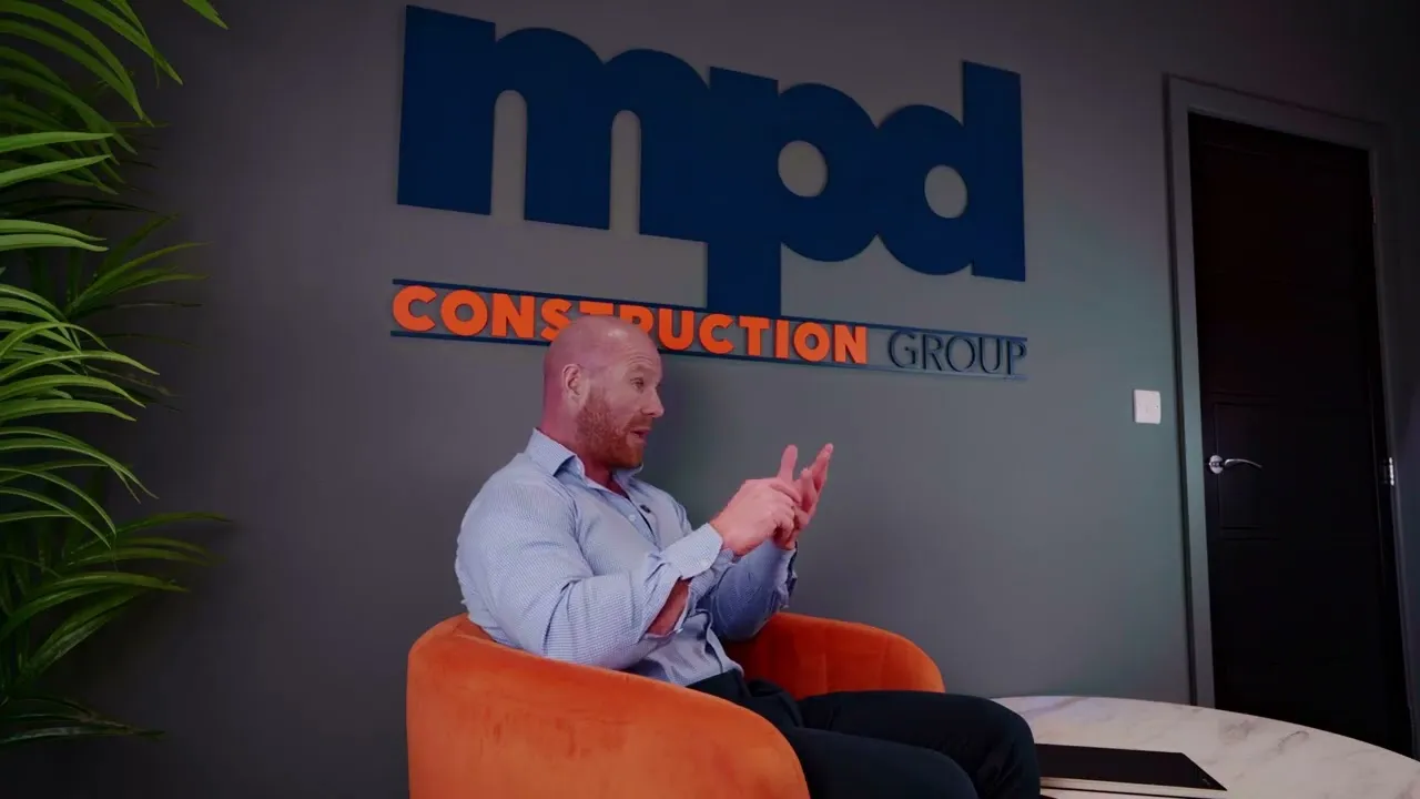 An MPD Construction Group director speaking in front of the company sign