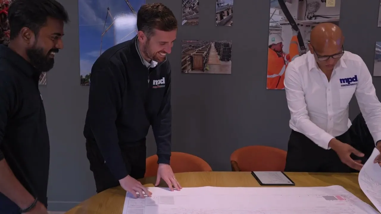The MPD Construction team reviewing drawings around a table