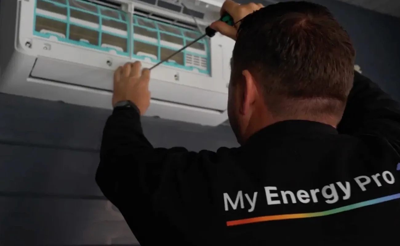 George Campbell servicing a wall-mounted air conditioning unit