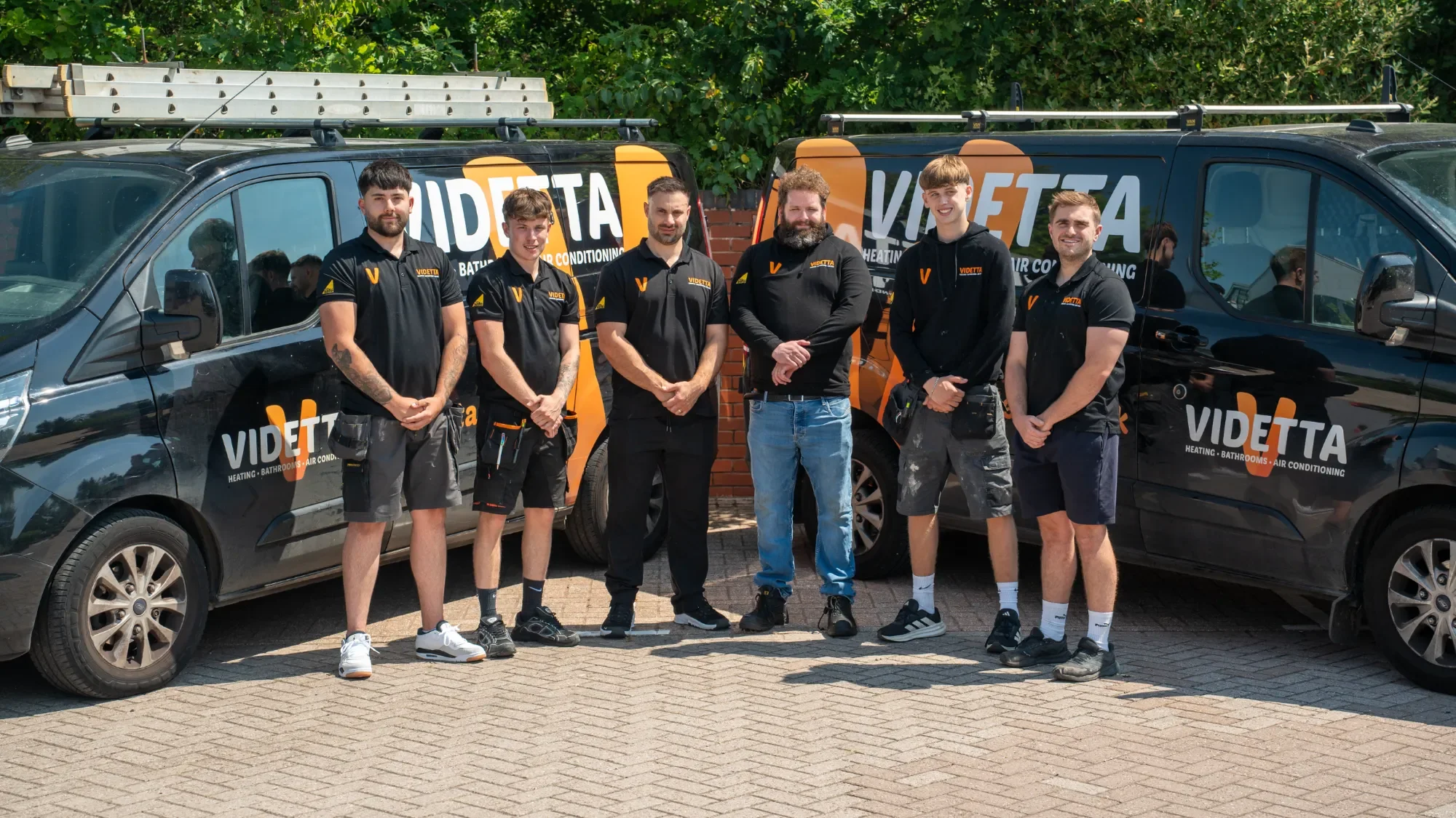 The Videtta Heating & Plumbing team in front of two of their branded vans